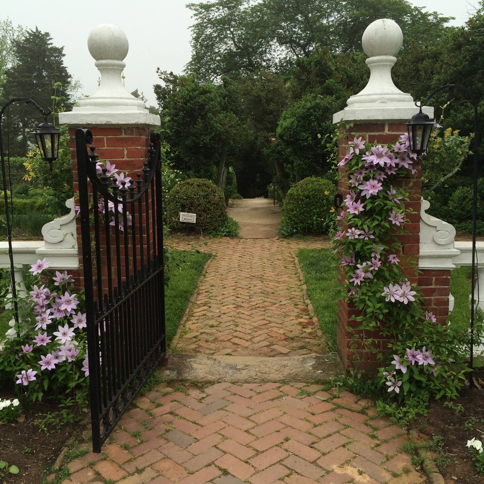 Brick and wrought iron gate with flowers leading to the walled garden